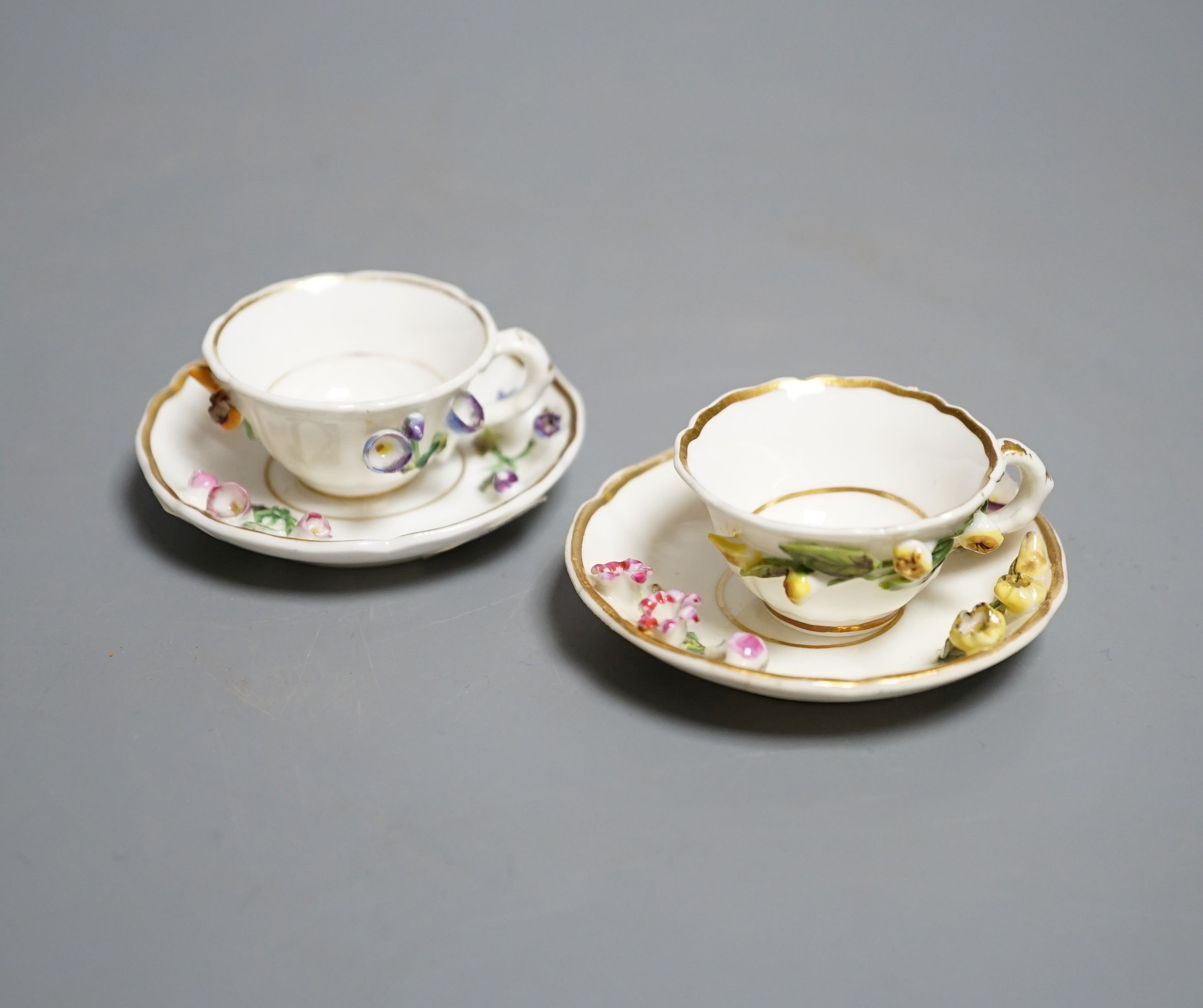 Two Rockingham miniature flower encrusted cups and saucers, c.1830. Provenance - Mona Sattin collection of miniature cups and saucers, collection no. 199 and 200.